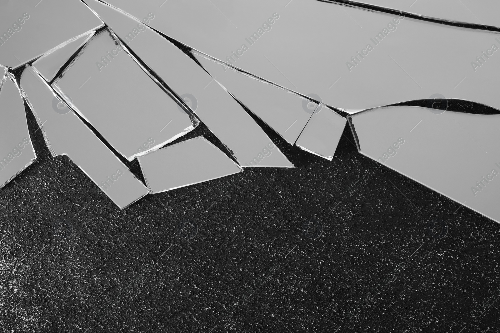 Photo of Shards of broken mirror on dark textured background, top view