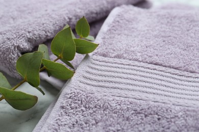 Violet terry towels and eucalyptus branch on table, closeup