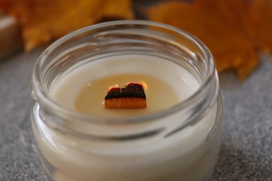 Burning scented candle on light gray table, closeup