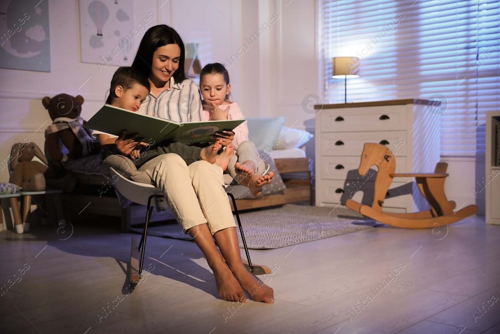 Photo of Mother reading bedtime story to her children at home