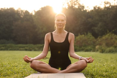 Beautiful woman practicing yoga on mat outdoors. Lotus pose