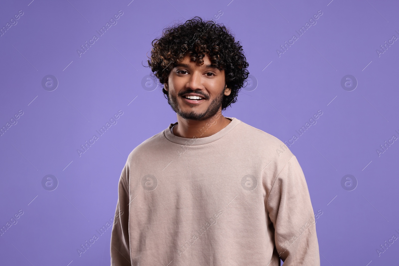 Photo of Handsome young smiling man on violet background