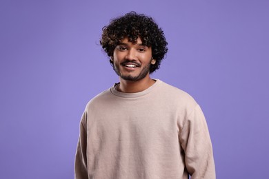 Handsome young smiling man on violet background