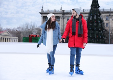 Image of Happy couple skating along ice rink outdoors