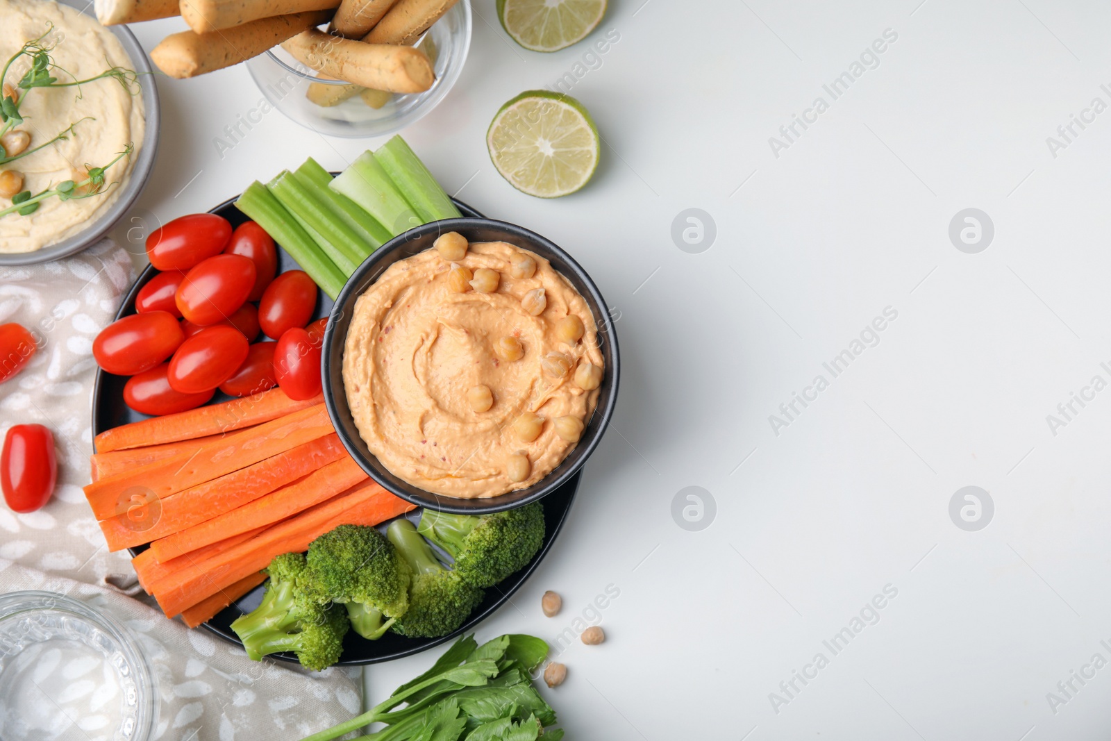 Photo of Plate with delicious hummus and fresh vegetables on white table, flat lay. Space for text