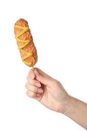 Woman holding delicious deep fried corn dog with mustard on white background, closeup