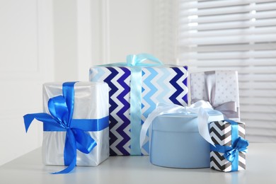 Photo of Heap of wrapped gift boxes on white table. Happy holiday