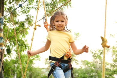 Little girl climbing in adventure park. Summer camp