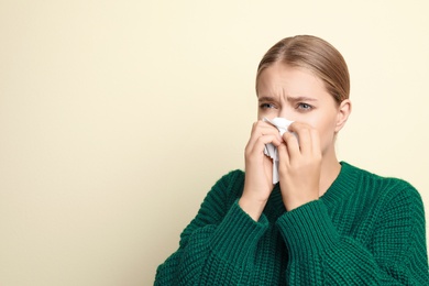 Image of Young woman sneezing on light background, space for text. Cold symptoms