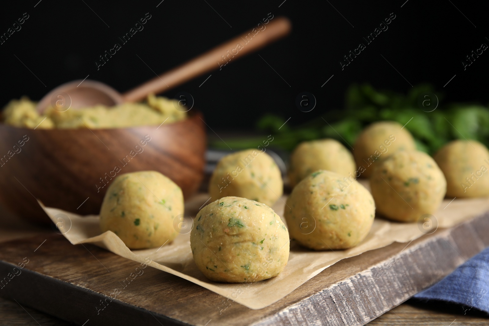 Photo of Wooden board with raw falafel balls on table, closeup