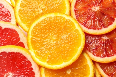 Photo of Slices of fresh citrus fruits as background, top view