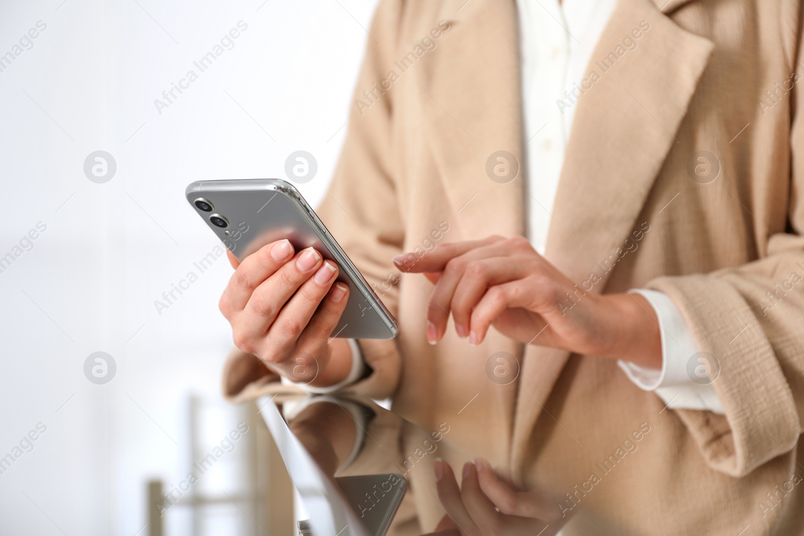 Photo of Young woman using modern smartphone indoors, closeup