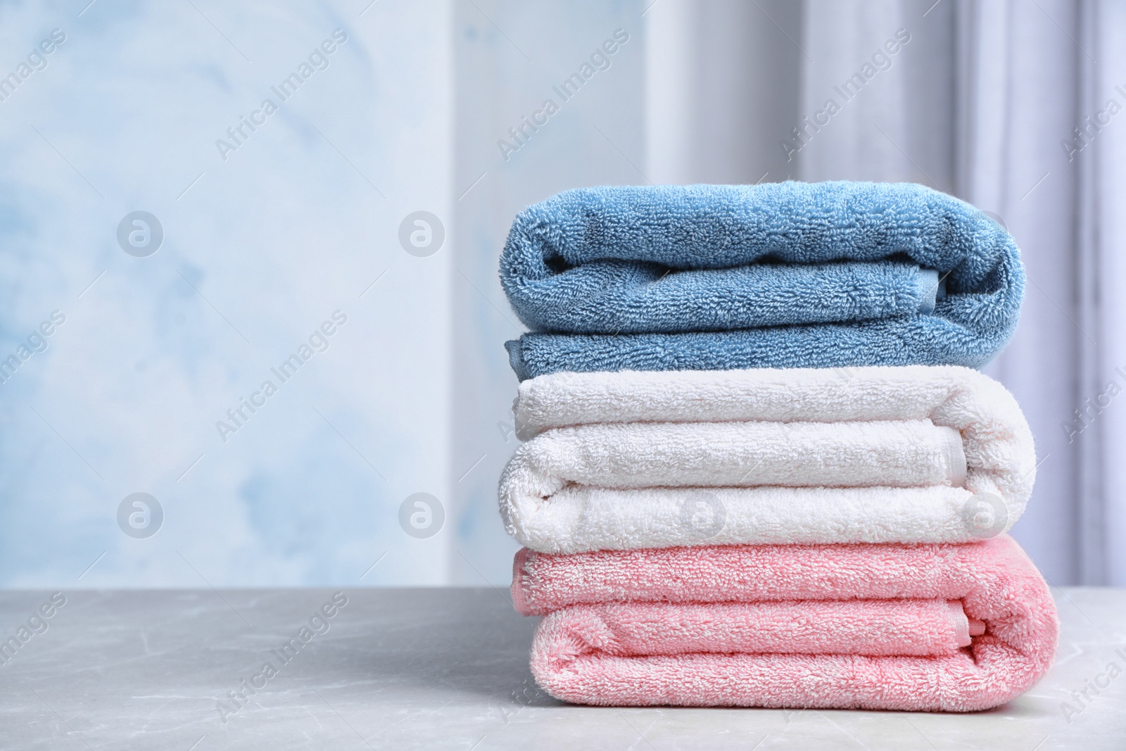 Photo of Stack of soft bath towels on table against blurred background. Space for text