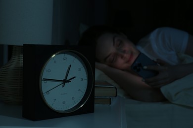 Woman using smartphone on bed at night, selective focus. Internet addiction