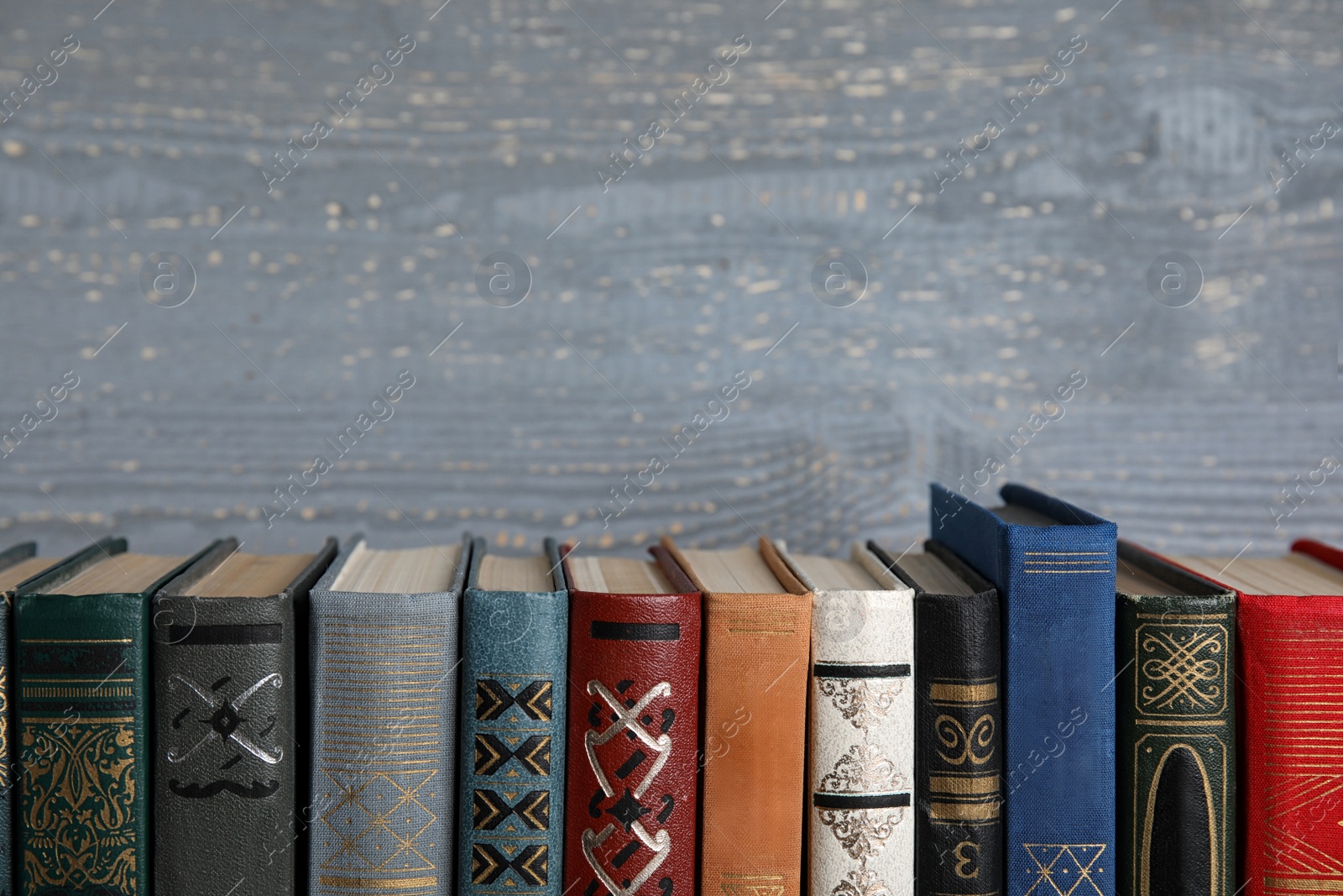 Photo of Stack of hardcover books on grey wooden background. Space for text