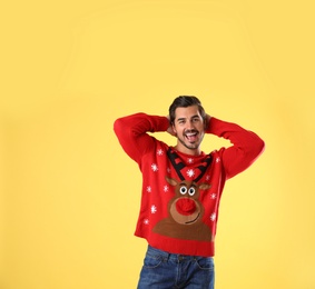 Photo of Portrait of happy young man in Christmas sweater on yellow background