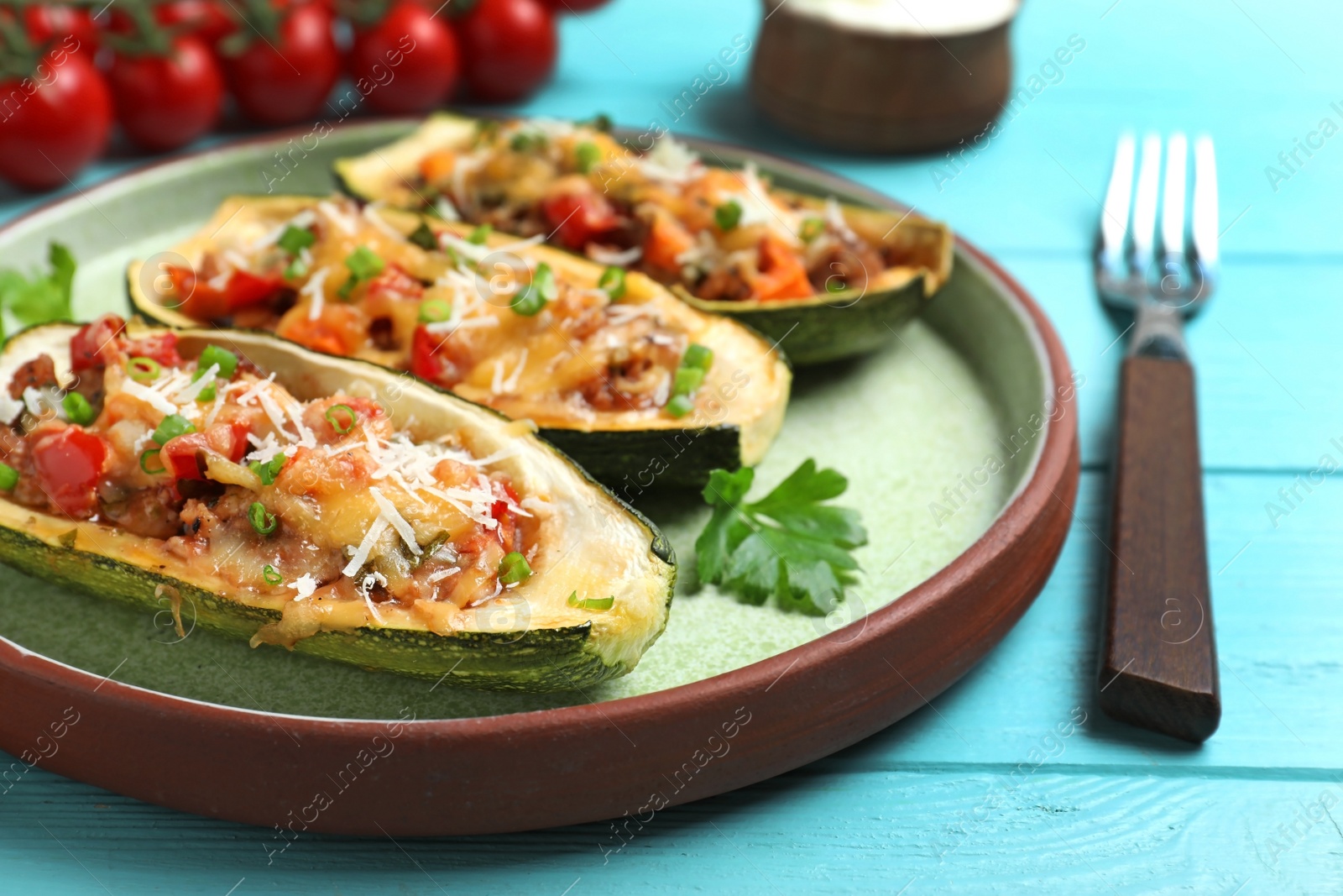 Photo of Delicious stuffed zucchini served on light blue wooden table, closeup