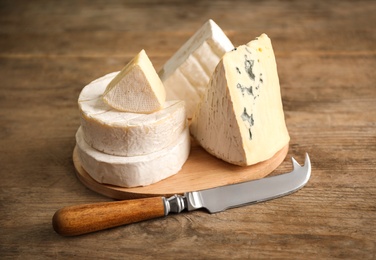 Different types of cheese and knife on wooden table