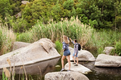 Photo of Cute young couple crossing river. Camping season