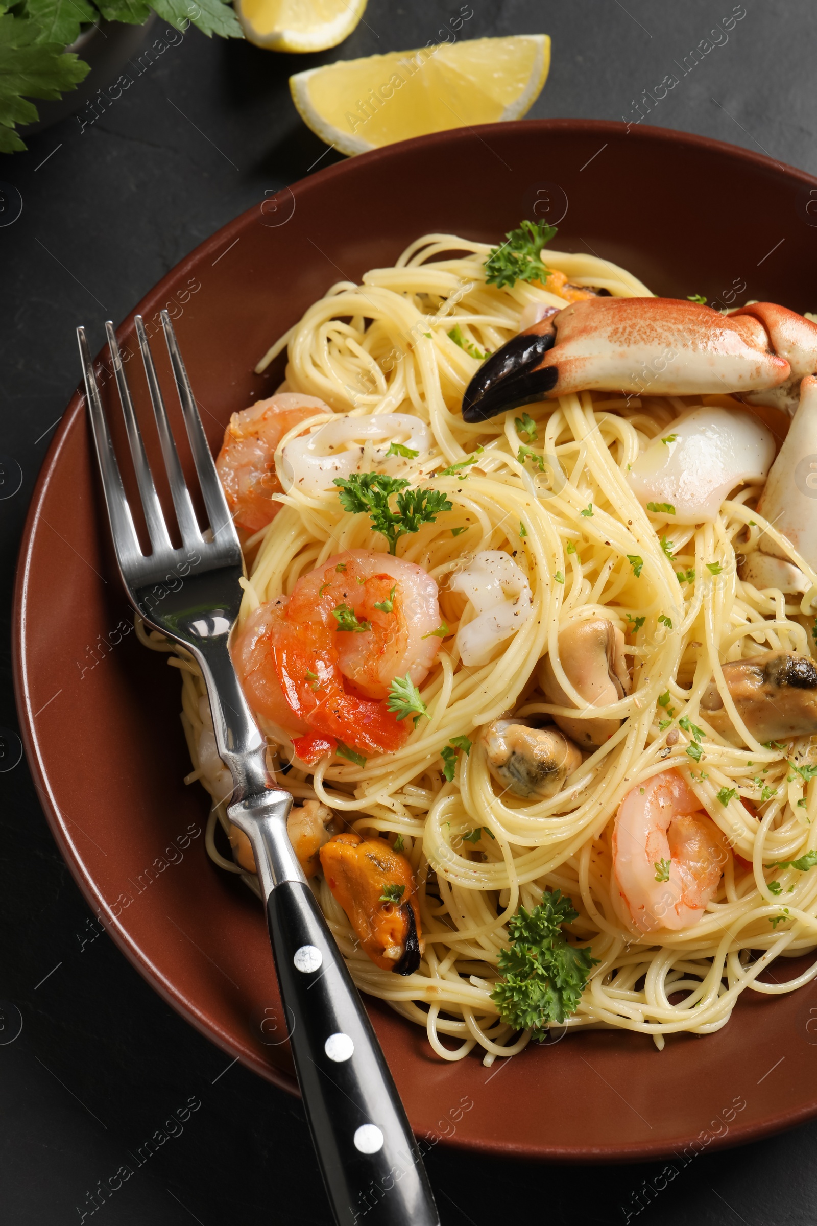 Photo of Delicious pasta with sea food served on black table, closeup