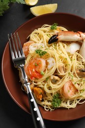 Photo of Delicious pasta with sea food served on black table, closeup