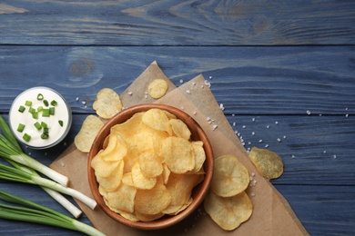 Flat lay composition with potato chips and sauce on wooden table. Space for text