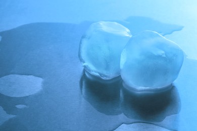 Photo of Crystal clear ice cubes on light blue background, space for text. Color tone effect