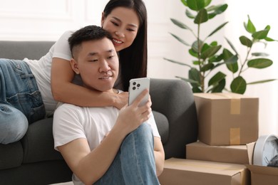 Photo of Happy couple with smartphone in their new apartment