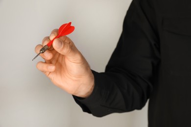 Photo of Man holding red dart on light background, closeup