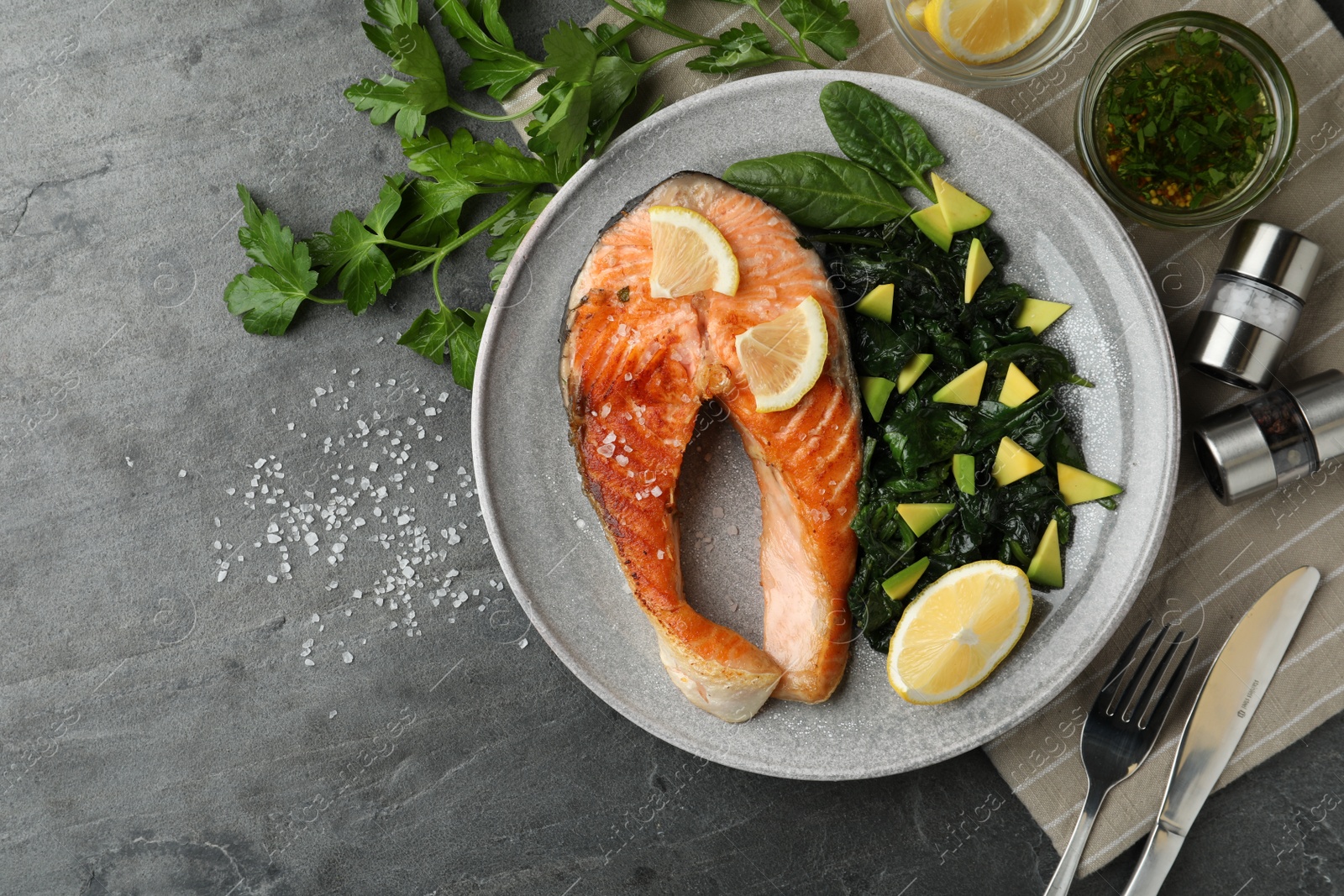 Photo of Tasty salmon with spinach served on grey table, flat lay