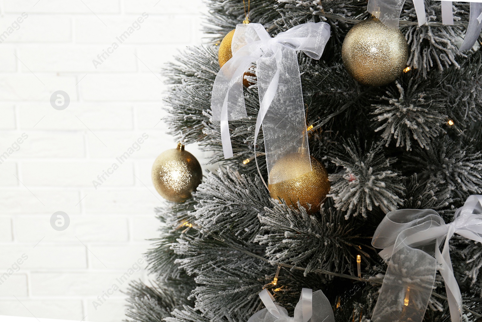 Photo of Decorated Christmas tree near white brick wall, closeup