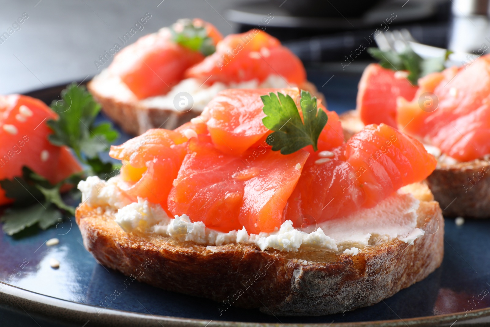 Photo of Tasty bruschettas with salmon, cream cheese and parsley on plate, closeup