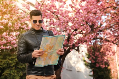 Happy male tourist with map on city street