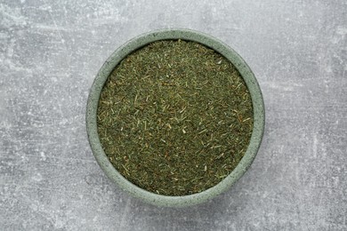 Dried dill in bowl on light grey table, top view