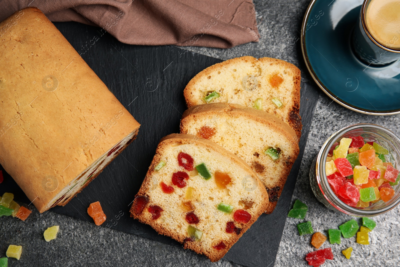 Photo of Delicious cake with candied fruits and coffee on grey table, flat lay