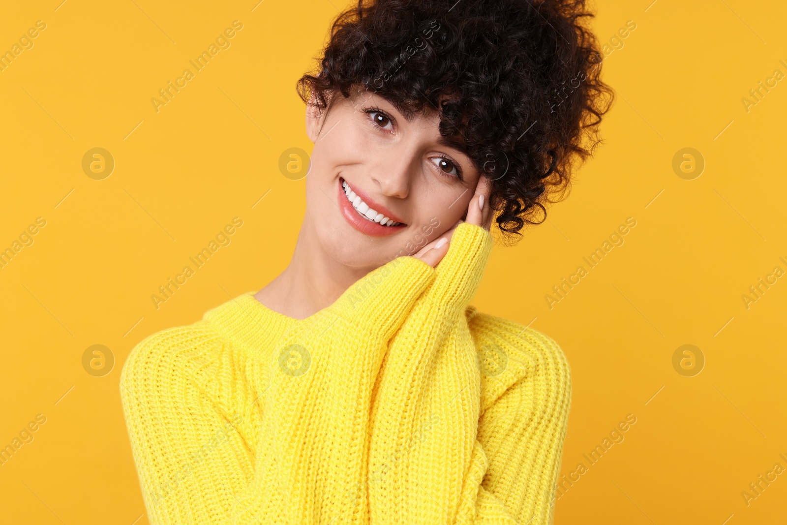 Photo of Happy young woman in stylish warm sweater on yellow background