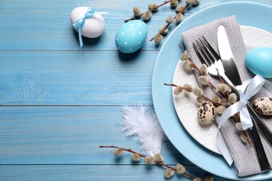 Photo of Festive Easter table setting with eggs on light blue wooden background, flat lay. Space for text