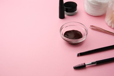 Photo of Eyebrow henna and professional tools on pink background, space for text