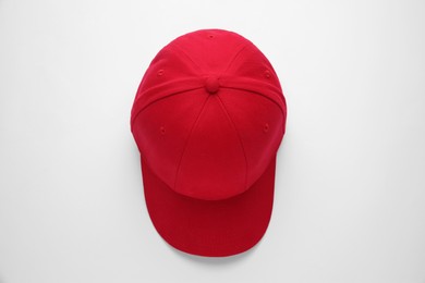 Photo of Stylish red baseball cap on white background, top view