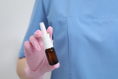 Photo of Doctor holding nasal spray on white background, closeup