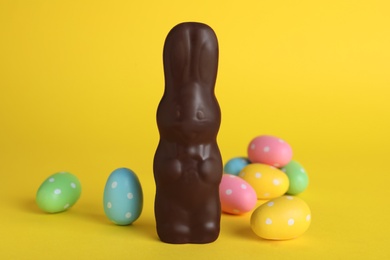 Photo of Chocolate Easter bunny and dyed eggs on yellow background