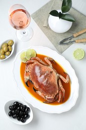 Photo of Delicious crab with sauce and lime served on white table, flat lay