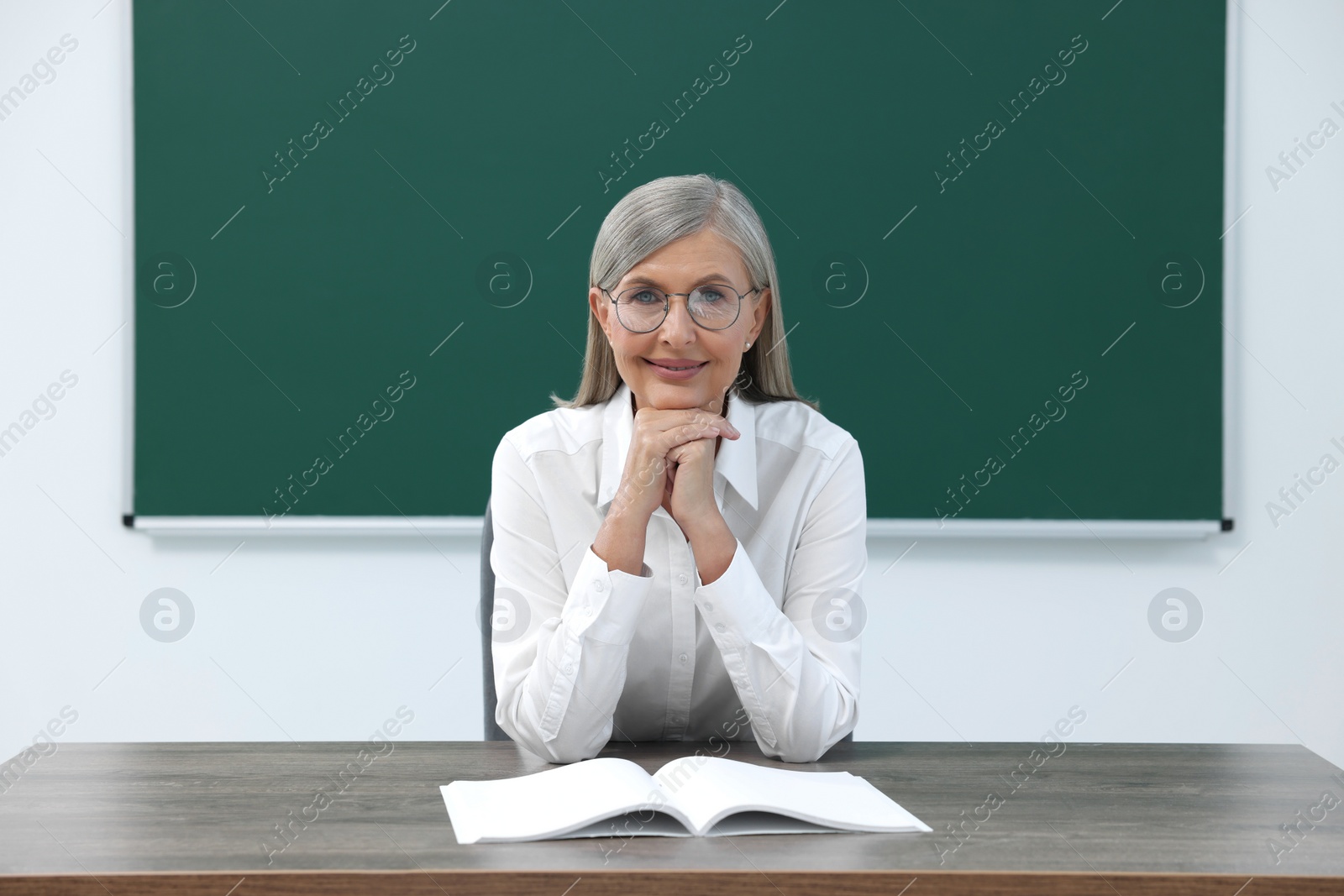 Photo of Portrait of professor sitting at desk in classroom