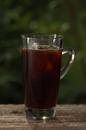 Photo of Glass of iced coffee on wooden table outdoors