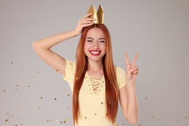 Photo of Beautiful young woman with princess crown under falling confetti on light grey background