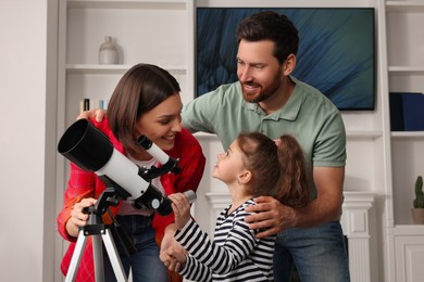 Photo of Happy family using telescope to look at stars in room
