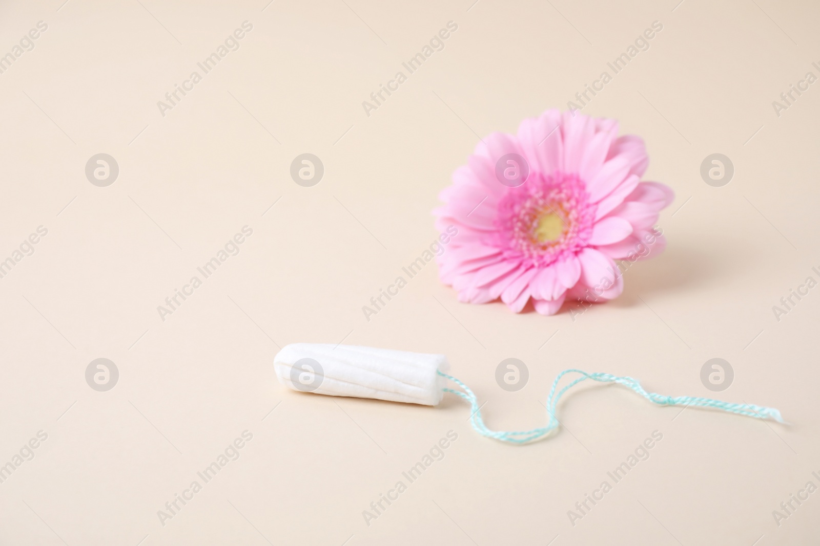 Photo of Hygienic tampon and flower on beige background. Gynecology concept