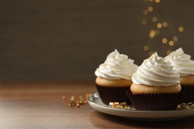 Photo of Delicious cupcakes decorated with cream on wooden table, space for text