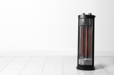 New modern electric heater on floor in room, space for text