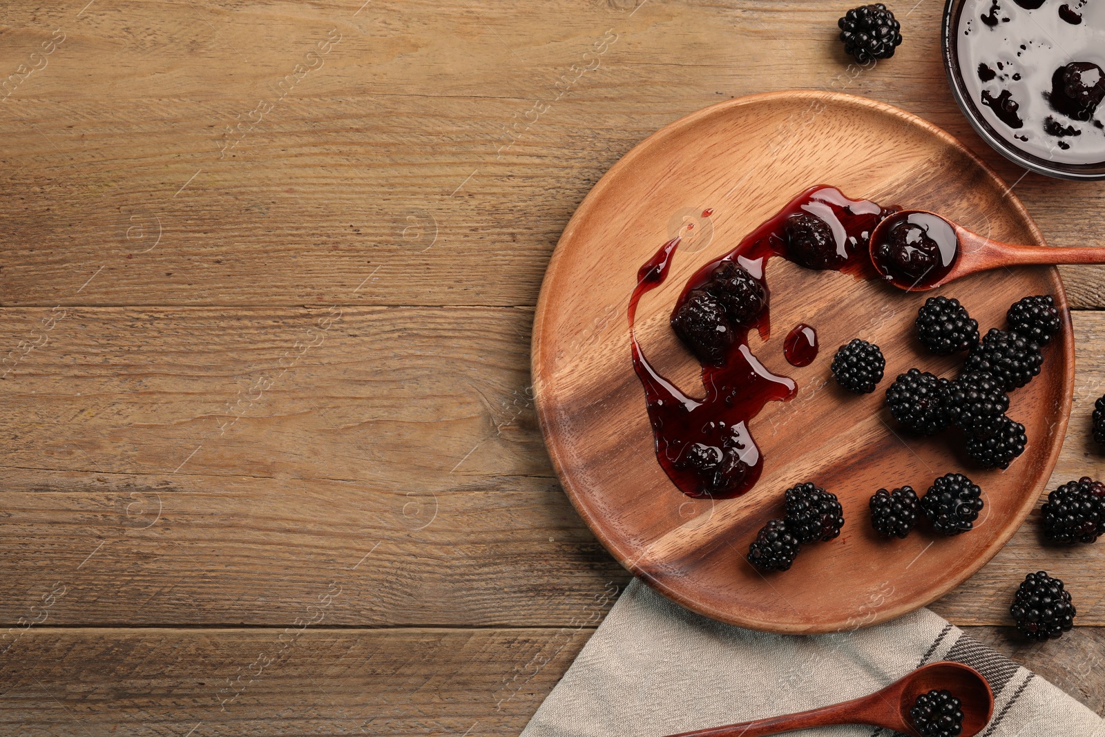 Photo of Tasty blackberry jam and fresh berries on wooden table, flat lay. Space for text